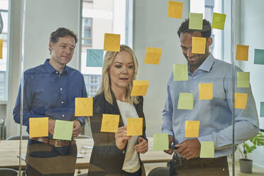 Business professionals planning strategy on adhesive notes in board room at office - AKLF00450