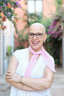 Happy mature woman with arms crossed standing at backyard - AGOF00208