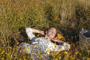 Junge Frau entspannt sich auf einer Wiese an einem sonnigen Tag - EIF02007