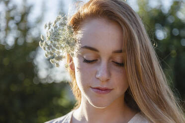 Beautiful woman with eyes closed wearing flowers on sunny day - EIF02008