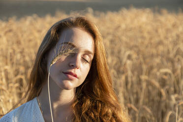 Frau mit Weizen auf geschlossenen Augen an einem sonnigen Tag - EIF02016