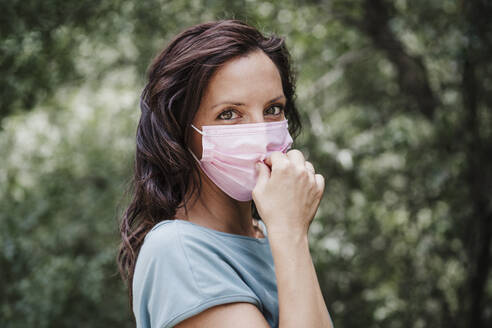 Woman wearing protective face mask in forest during COVID-19 - EBBF04478