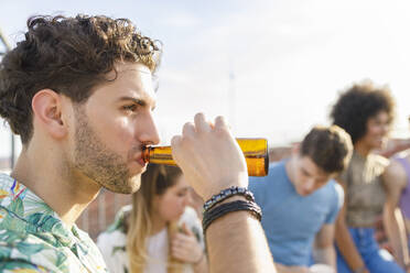 Junger Mann trinkt Bier auf einer Party - IFRF00980