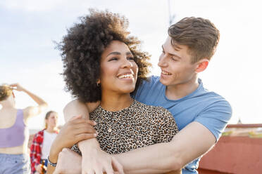 Young man with arms around girlfriend during terrace party - IFRF01005