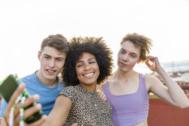 Männliche und weibliche Freunde nehmen Selfie durch Smartphone auf Terrasse - IFRF01027