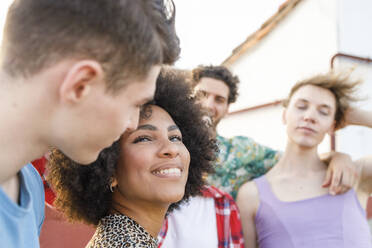 Young woman looking at boyfriend while friends in background on rooftop - IFRF01031