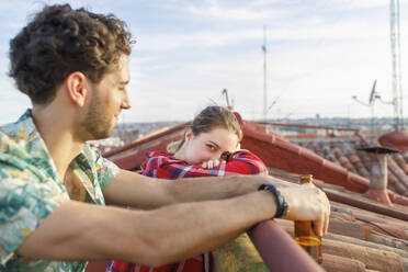 Junge Frau lehnt sich mit ihrem Freund auf dem Dach an ein Geländer - IFRF01039