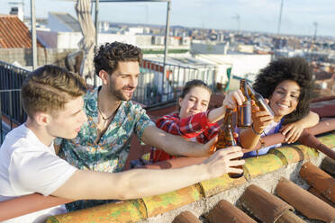 Junge multiethnische Freunde stoßen am Wochenende auf dem Dach mit Bierflaschen an - IFRF01040