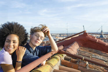 Glückliche junge Frau lehnt sich auf der Schulter eines Freundes auf dem Dach an - IFRF01046