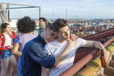 Young man embracing male friend on terrace during party - IFRF01049