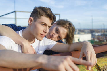 Young man looking at male friend on rooftop - IFRF01050