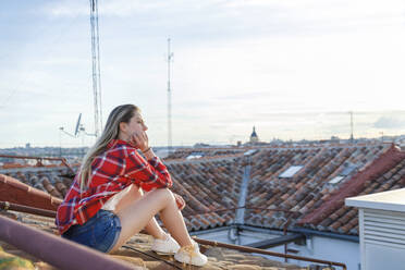 Young woman day dreaming while sitting on rooftop - IFRF01052