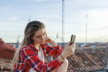 Junge Frau benutzt Smartphone auf dem Dach - IFRF01055