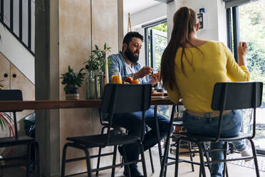 Man having breakfast with woman while sitting at home - ASGF01009