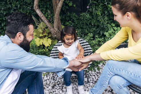 Lächelnde Familie stapelt die Hände beim Spielen im Hinterhof - ASGF01017