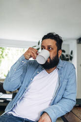 Man drinking coffee while sitting at home - ASGF01064