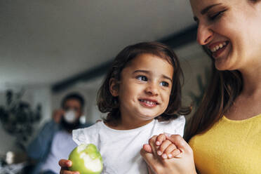 Smiling mother holding hands of cute daughter at home - ASGF01070