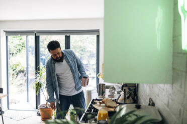 Man checking stove in kitchen at home - ASGF01073