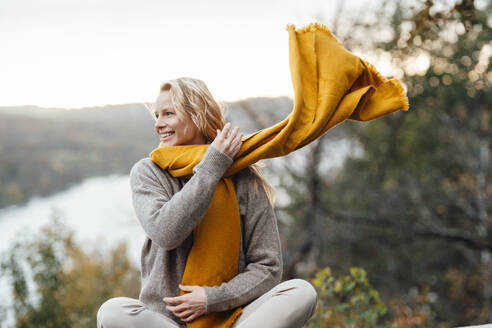 Smiling woman looking away wearing scarf during autumn - JOSEF05375