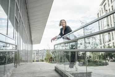 Businesswoman contemplating while leaning on railing at office park - VPIF04480