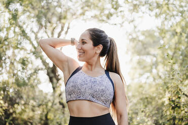 Lächelnde Sportlerin beim Muskeltraining im Wald - EBBF04516