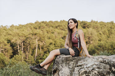 Weiblicher Wanderer mit Rucksack auf einem Felsen sitzend - EBBF04524