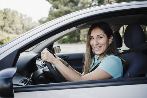 Lächelnde junge Frau am Steuer eines Autos - EBBF04540