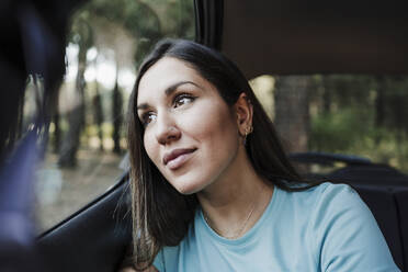 Schöne junge Frau, die im Auto sitzend nachdenkt - EBBF04551