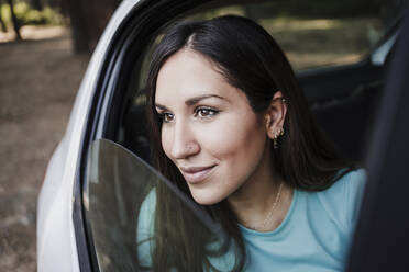 Beautiful young woman looking through car window - EBBF04553