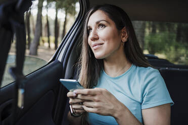 Junge Frau mit Handy in der Hand im Auto sitzend - EBBF04554