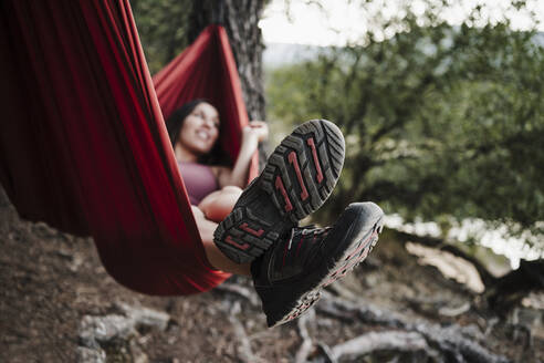 Woman relaxing on hammock in forest during vacation - EBBF04571