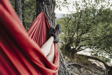 Young woman with feet up relaxing on hammock - EBBF04575