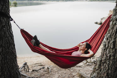 Woman looking up while relaxing on hammock - EBBF04576