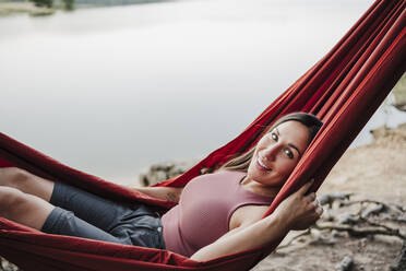 Beautiful woman smiling while relaxing on hammock - EBBF04578