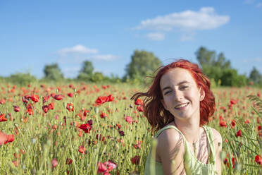 Teenage girl smiling in poppy field during sunny day - BFRF02355