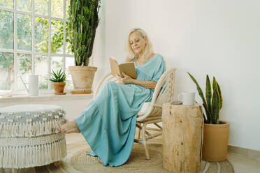 Senior woman reading book at home - ERRF04930