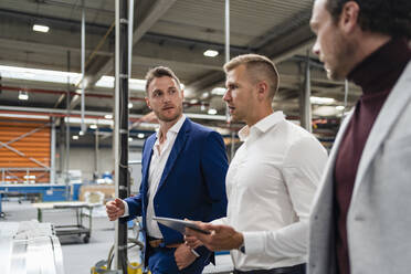 Male inspector holding digital tablet while discussing with businessmen at industry - DIGF16143