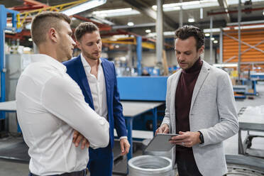 Business team discussing over digital tablet at industry - DIGF16146