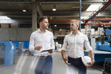 Männliche Fachleute diskutieren beim Gehen in einer Fabrik - DIGF16153