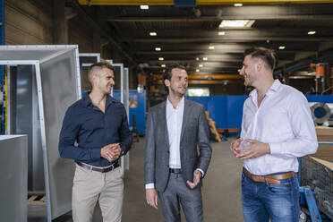 Smiling male professionals having discussion at factory - DIGF16202