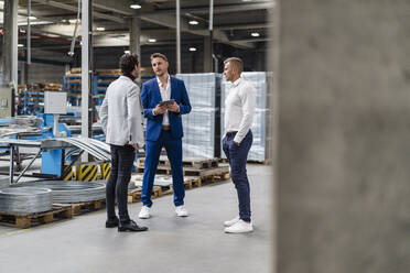 Male professionals having discussion while standing in factory - DIGF16236