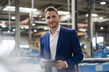 Lächelnder männlicher Fachmann mit digitalem Tablet in der Industrie - DIGF16243