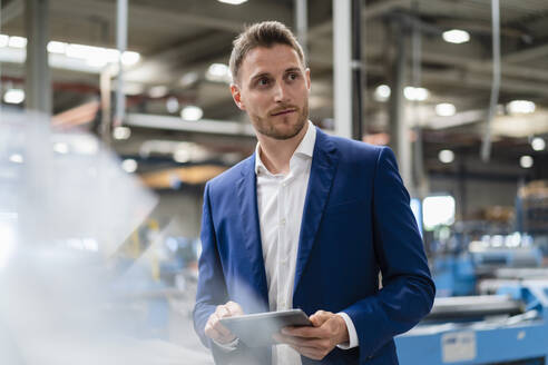 Umsichtiger Geschäftsmann mit digitalem Tablet in der Industrie - DIGF16246