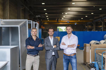 Businessmen with arms crossed standing in factory - DIGF16275