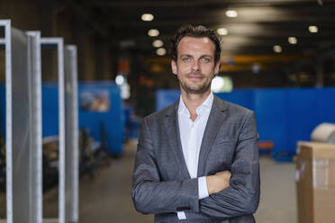 Male professional with arms crossed standing in factory - DIGF16277