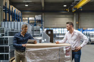 Young businessman using digital tablet while standing with male colleague at factory - DIGF16287