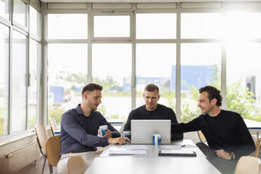 Male professionals using laptop while working during meeting - DIGF16302