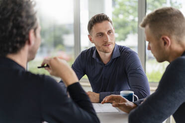 Male professional discussing with colleagues during meeting at office - DIGF16304