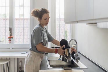 Frau füllt Kaffeekanne aus Wasserhahn in Küche - MEUF03729