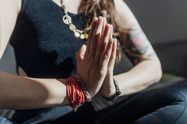 Frau mit verschränkten Händen übt Yoga zu Hause - MEUF03749